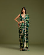 Model wearing a bottle green satin crepe saree with zari and sequin work.