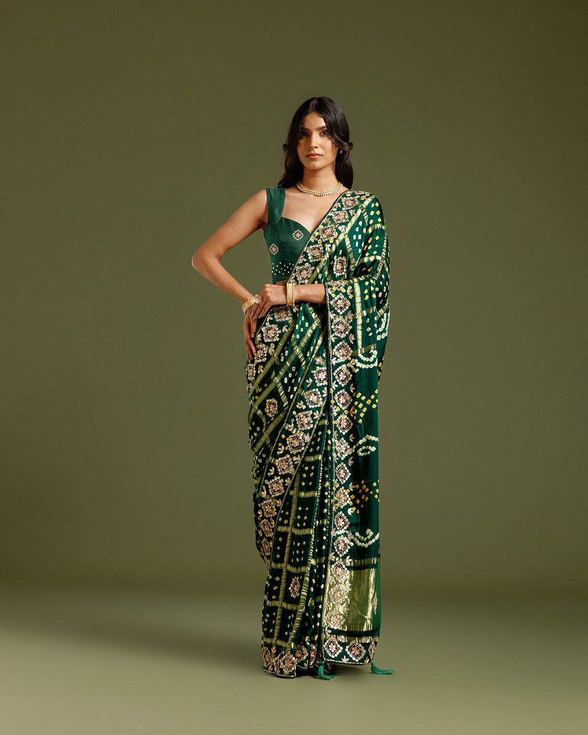 Model wearing a bottle green satin crepe saree with zari and sequin work.